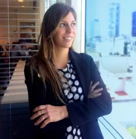 Mujer con chaqueta negra mira por la ventana de una oficina.