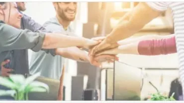 Grupo de personas uniendo sus manos en un gesto de trabajo en equipo.