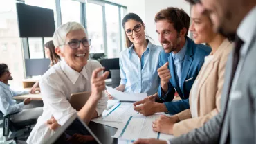 Grupo de personas sonrientes en una reunión de trabajo en la oficina.