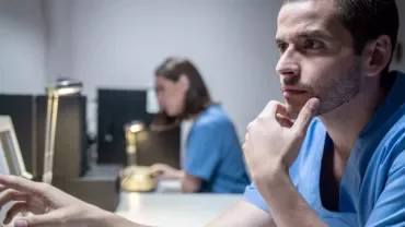 Hombre en uniforme médico mirando una pantalla.
