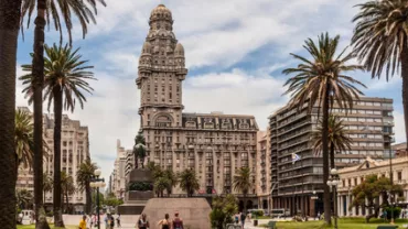 Plaza con palmeras y edificio histórico en un día soleado.