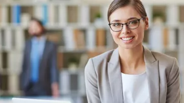 Mujer sonriente con gafas en oficina moderna.