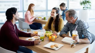 Grupo de personas charlando mientras almuerzan en una cafetería.