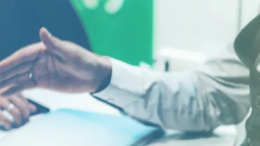 Persona extendiendo la mano durante una reunión de oficina.