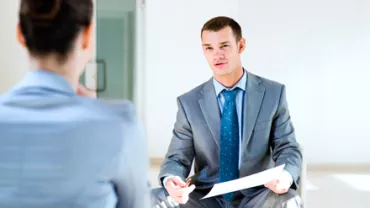 Dos personas en una entrevista; una de ellas sostiene un papel.