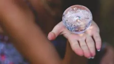 Persona sosteniendo una esfera de cristal en su mano.