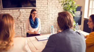 Mujer en entrevista de trabajo, sentada frente a tres personas en una oficina.
