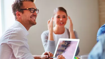 Personas sonriendo mientras trabajan juntas en una oficina.