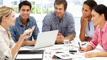 Equipo de personas sonriendo en una reunión de oficina.