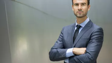 Hombre de negocios de pie, con traje oscuro.