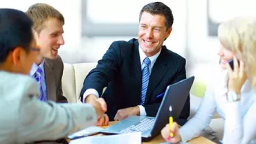Grupo de personas en una reunión de negocios, sonriendo y estrechando manos.
