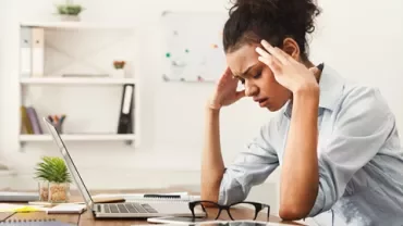 Mujer estresada frente a una computadora portátil en una oficina.