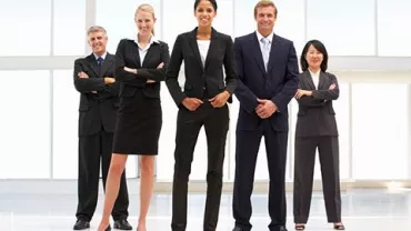 Grupo de profesionales de pie sonriendo con ropa formal.