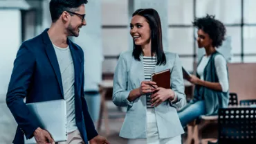 Dos profesionales conversando alegremente en una oficina moderna.