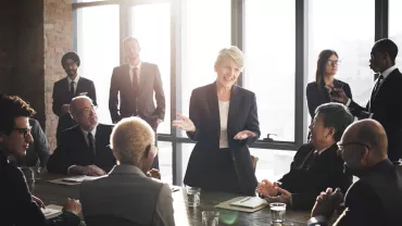 Personas en traje en reunión de negocios en oficina iluminada.
