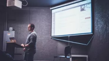 Persona presentando una diapositiva en una sala oscura.