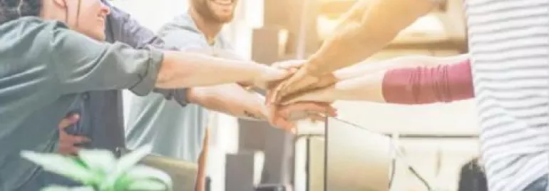 Grupo de personas uniendo sus manos en un gesto de trabajo en equipo.