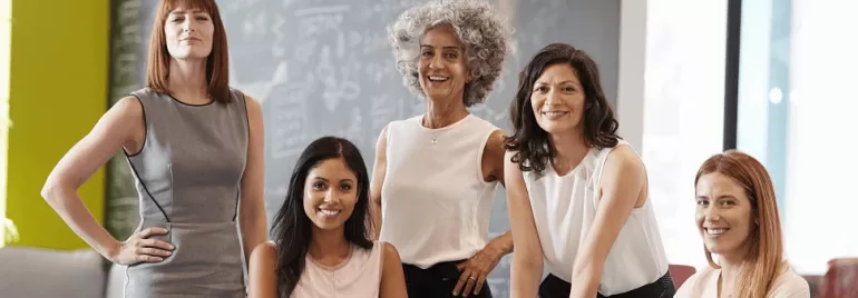 Cinco mujeres posando en una oficina moderna.