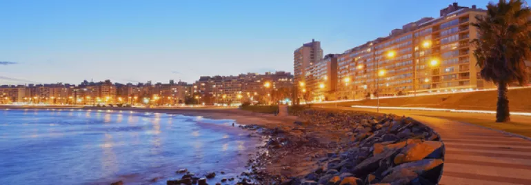 Vista nocturna de la costa con luces y edificios en Montevideo.