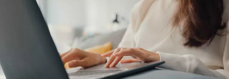 Mujer trabajando en una laptop en un sofá.