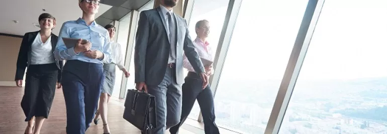 Grupo de personas caminando en un pasillo de oficinas con vista panorámica.