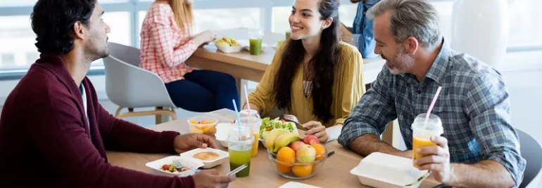 Grupo de personas charlando mientras almuerzan en una cafetería.