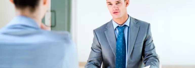 Dos personas en una entrevista; una de ellas sostiene un papel.