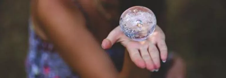 Persona sosteniendo una esfera de cristal en su mano.