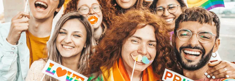 Grupo de amigos felices con accesorios de arco iris y carteles de amor.