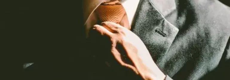 Hombre ajustando su corbata en un traje formal.
