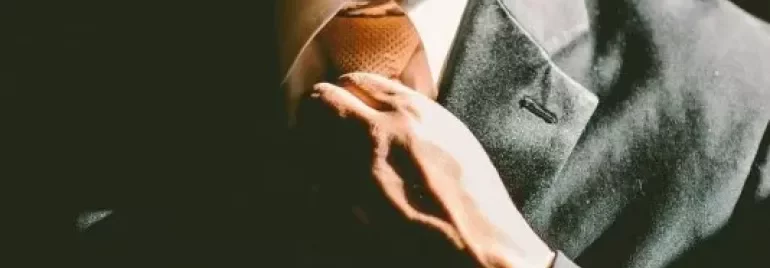 Hombre ajustando su corbata en un traje formal.