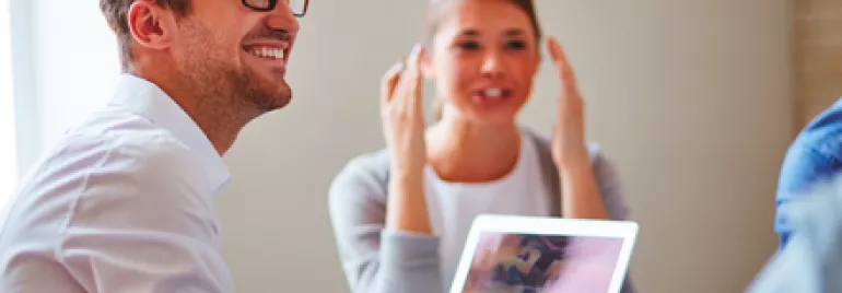Personas sonriendo mientras trabajan juntas en una oficina.