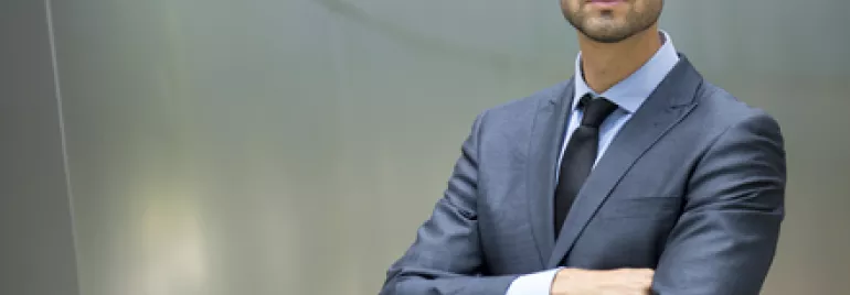 Hombre de negocios de pie, con traje oscuro.