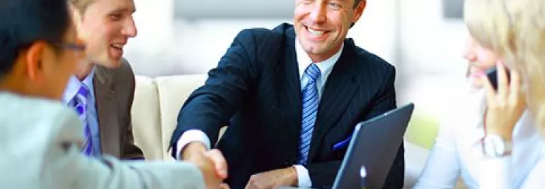 Grupo de personas en una reunión de negocios, sonriendo y estrechando manos.