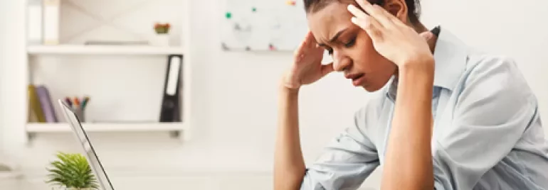 Mujer estresada frente a una computadora portátil en una oficina.