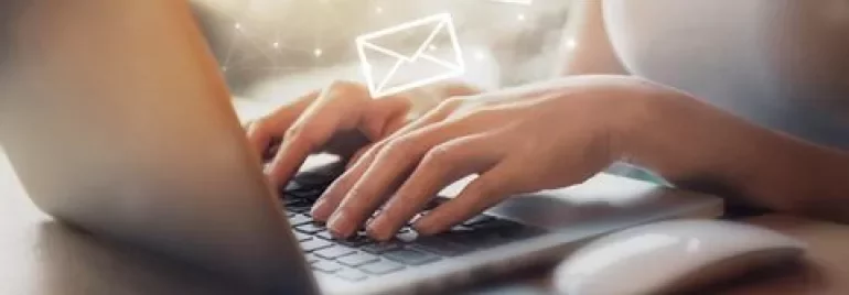 Persona usando una laptop con íconos de correo flotando.