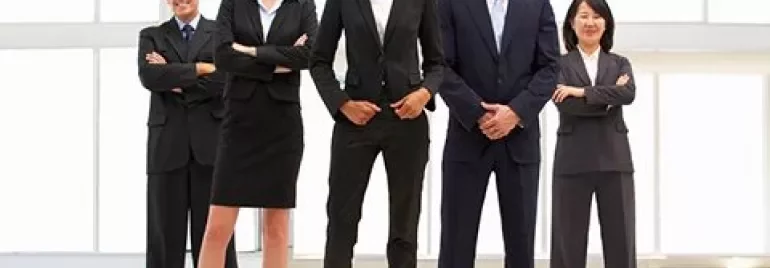 Grupo de profesionales de pie sonriendo con ropa formal.