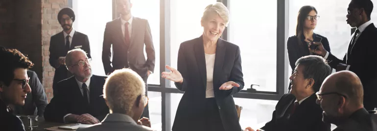 Personas en traje en reunión de negocios en oficina iluminada.