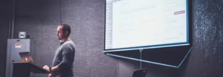 Persona presentando una diapositiva en una sala oscura.