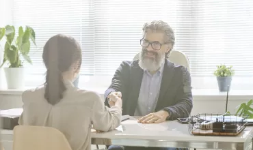 Hombre y mujer dándose la mano en una oficina luminosa.