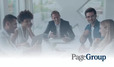 Reunión de trabajo en PageGroup, cinco personas sonrientes alrededor de una mesa.