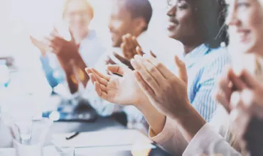 Grupo de personas aplaudiendo durante una reunión.