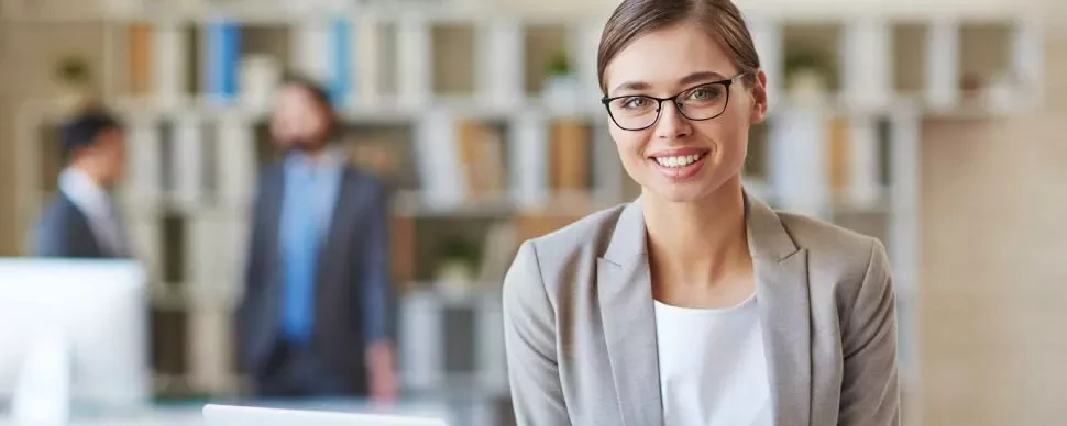 Mujer sonriente con gafas en oficina moderna.