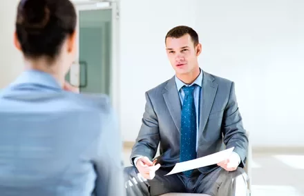 Dos personas en una entrevista; una de ellas sostiene un papel.