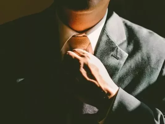 Hombre ajustando su corbata en un traje formal.