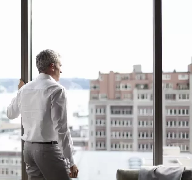 Hombre mirando por la ventana a edificios de la ciudad.