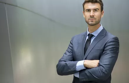 Hombre de negocios de pie, con traje oscuro.