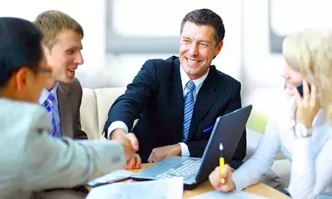 Grupo de personas en una reunión de negocios, sonriendo y estrechando manos.