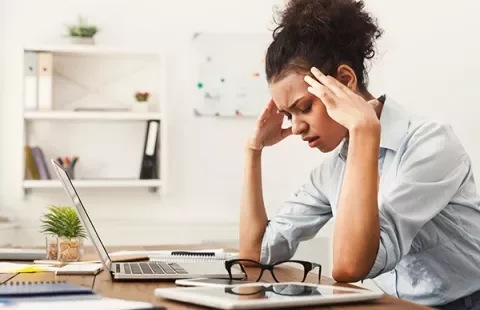 Mujer estresada frente a una computadora portátil en una oficina.