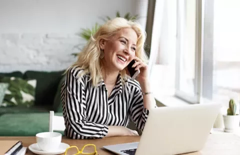Mujer sonriendo mientras habla por teléfono en casa.